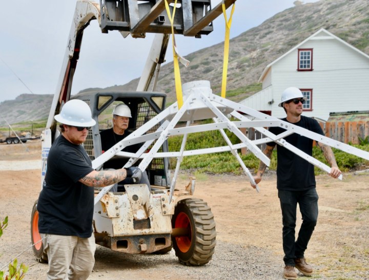 Ryan and Nick steady the roof frame as Neil drives it to the waiting crane. (Photo by Kim Fahlen.)