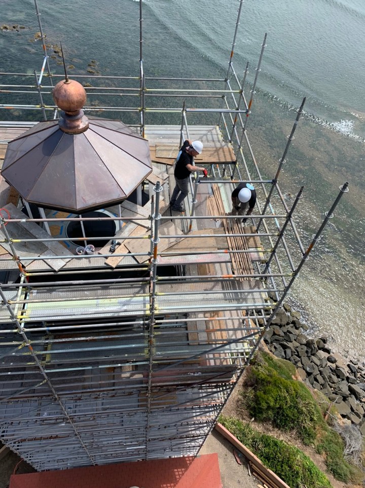 Copper roof panels, chimney and ventilator ball have been put back in place. Nick and Ryan shuffle endless components. (Photo by Kim Fahlen.)