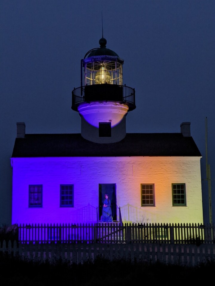 Lighthouse at night lit up with purple and gold.