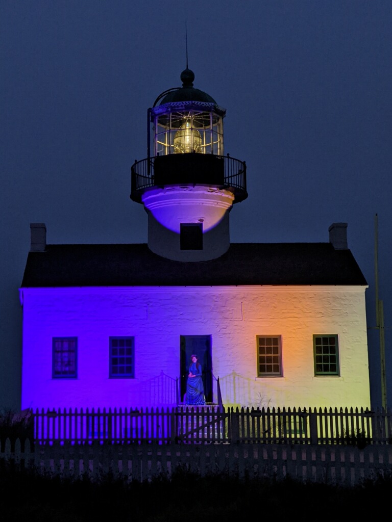 Lighthouse at night lit up with purple and gold.