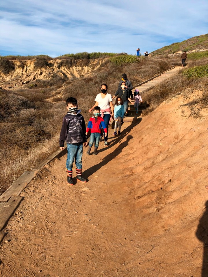 Family wearing face masks walking along dirt trail