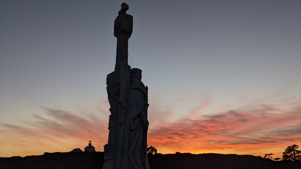 Shadow of statue at sunset with orange sky