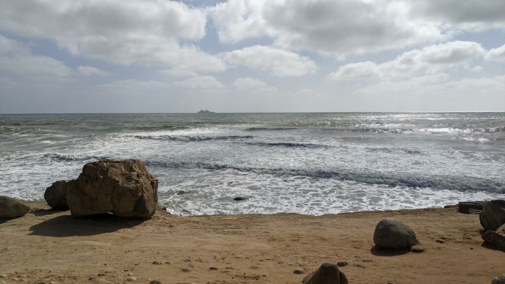 A view of the ocean from a cliff edge with large boulders in the foreground
