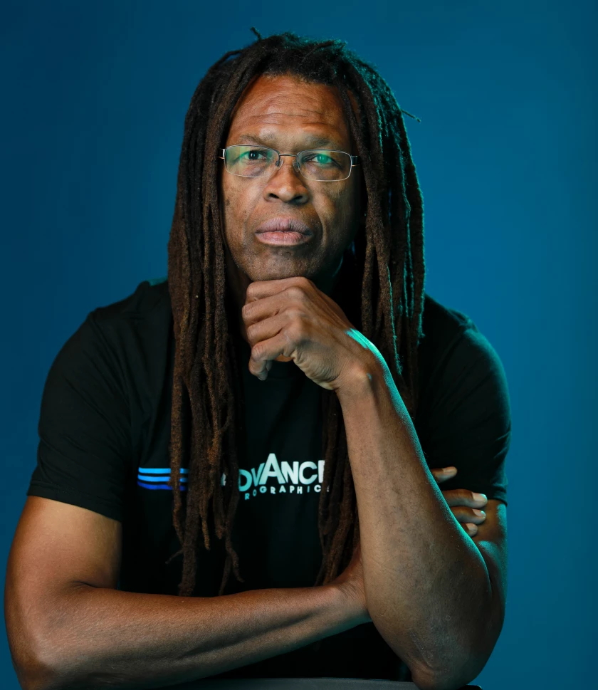 A man in a black shirt, long hair and glasses