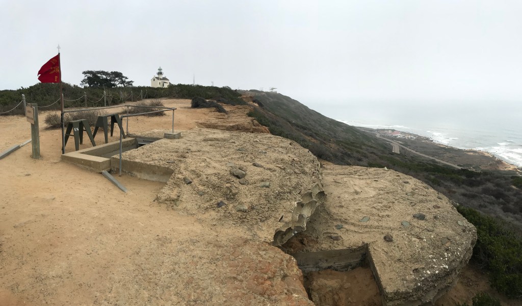 A bunker built into a hillside. A curved concrete roof blends into the hillside hiding it.
