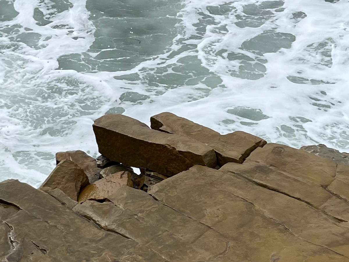 Large brown rectangular chunks of rock breaking loose from cliff