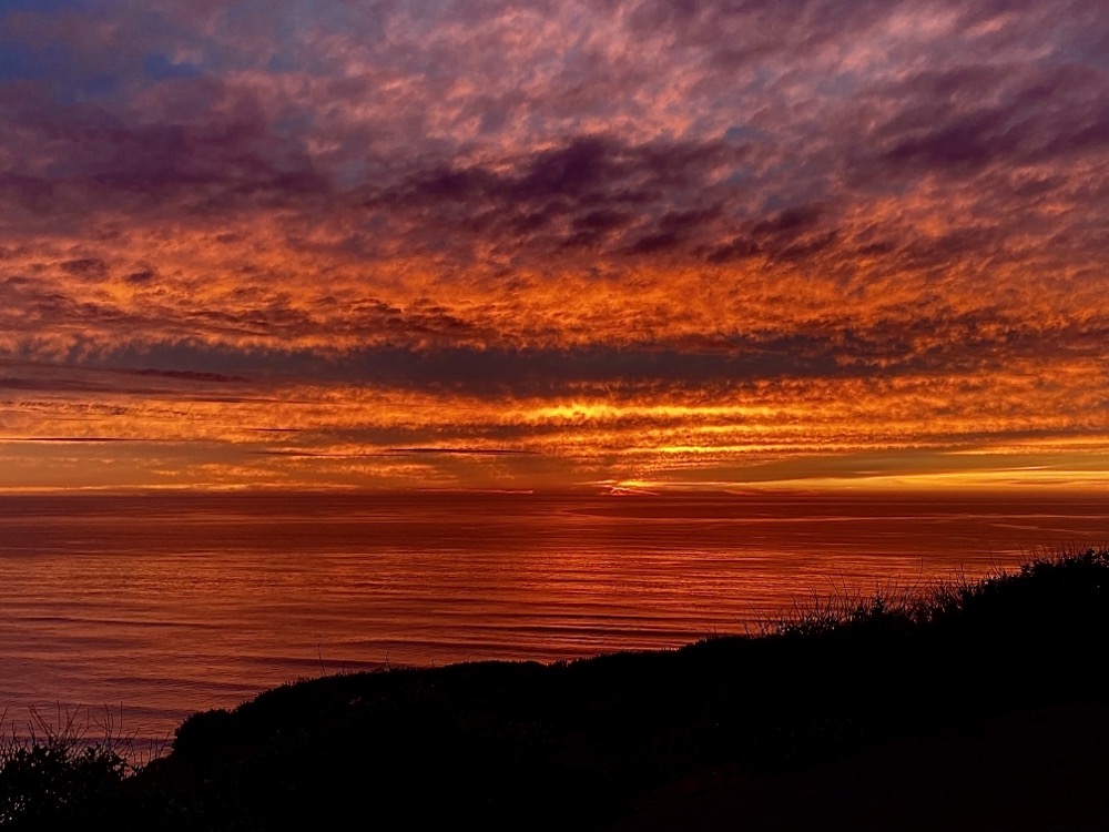 A sunset with orange clouds over the ocean