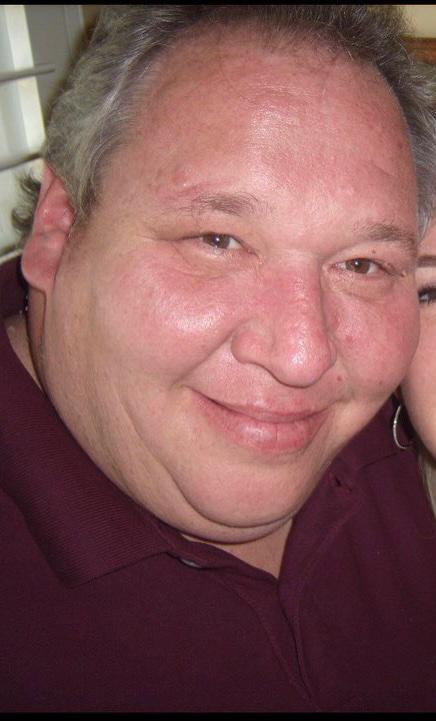 A smiling man in a maroon shirt