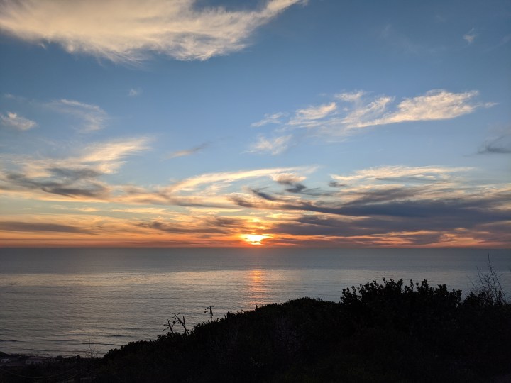 An orange sunset over the Pacific Ocean viewed from the Event Bluff at Cabrillo National Monument.