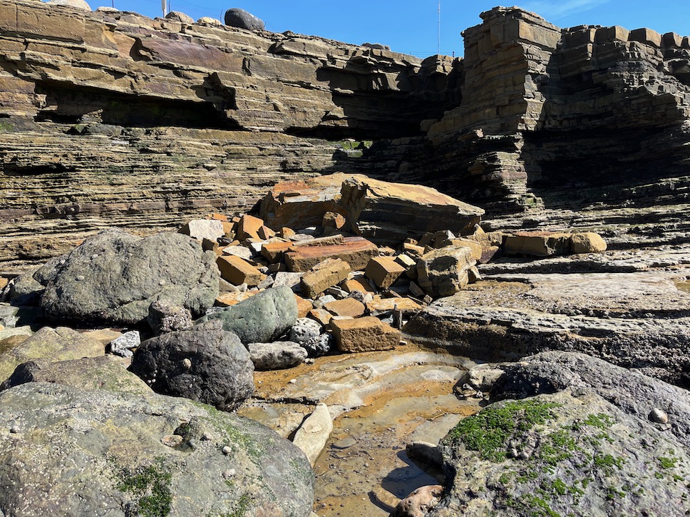 A collapse of large pieces of rock at the bottom of a cliff.