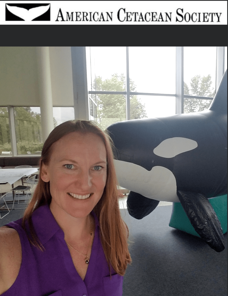 A woman stands in front of a whale model